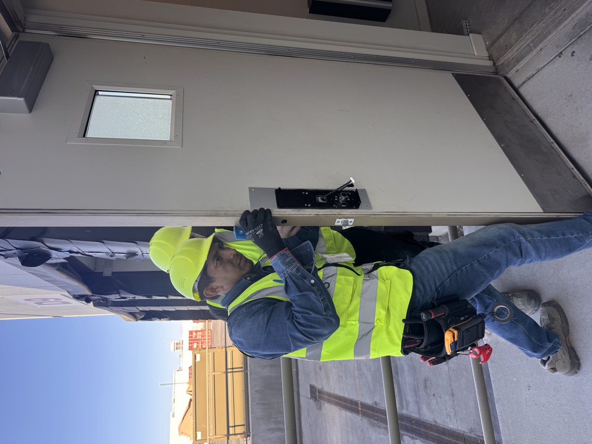 An IETEL technician installing access control hardware on an exterior door at the Nampa facility.